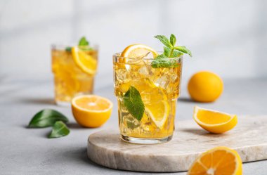 İki bardak buzlu içecek limonlu ve naneli mermer bir tahta üzerinde gölge ve narenciye meyveli. Sıcak bir yaz gününde soğuk çay ya da limonata konsepti. Ön görünüm.