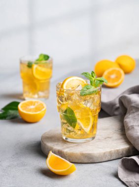 İki bardak buzlu içecek limonlu ve naneli mermer bir tahta üzerinde gölge ve narenciye meyveli. Sıcak bir yaz gününde soğuk çay ya da limonata konsepti. 