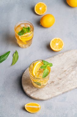 Limonlu buzlu çay, mermer bir tahtanın üzerinde nane şekeri ve narenciye arkaplanı. Sıcak bir yaz gününde ferahlatıcı içecek ya da limonata konsepti. Üst görünüm.