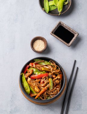 Hafif arka planda soba şehriyeli, etli ve sebzeli kızartma. Yemek çubukları, soya sosu ve susamlı Asya fast-food konsepti. Üst görünüm.