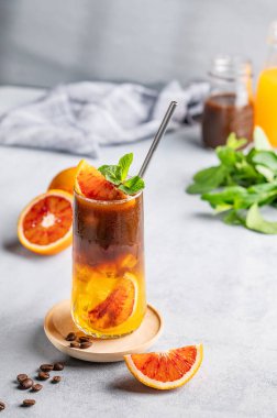 Kahve çekirdekleri, narenciye ve sabah gölgeleriyle mavi zemin üzerinde buzlu ve naneli uzun bir bardakta portakal suyu (yaban mersini) ile espresso kahvesi. Son moda Asya ferahlatıcı içeceği.