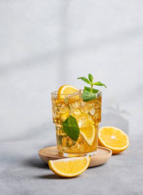 Limonlu buzlu içecek, arka planda gölgesi ve narenciye meyveli bir bardakta nane şekeri. Sıcak bir yaz gününde soğuk çay ya da limonata konsepti. Ön görünüm.
