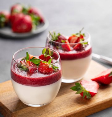 Çilekli ve kremalı panna cotta bardakta, tahta tahtada taze böğürtlen ve yakın plan gri. Geleneksel İtalyan tatlı konsepti. 