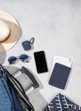 Arka planda seyahat aksesuarları, şapka ve güneş gözlüğü olan düz bir bavul. Seyahat konsepti. Üst görünüm ve kopyalama alanı.