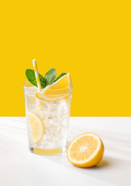 Limonlu, naneli ve buzlu soğuk bir limonata. Sarı ve beyaz arka planda. Yaz günlerinde ferahlatıcı ve sağlıklı bir içecek konsepti. Boşluğu kopyala.