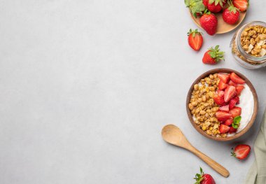 Tahta bir kasede taze böğürtlenli doğal yoğurt ve çilek. Sağlıklı ve besleyici kahvaltı konsepti. Üst görünüm ve kopyalama alanı.