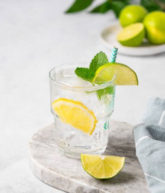 Limonlu, limonlu, naneli ve buzlu mojito kokteyli veya tonik. Hafif bir arka planda narenciye meyveli ferahlatıcı içecek konsepti. 