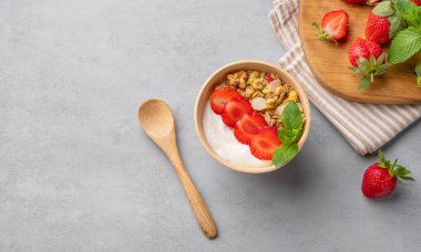 Doğal yoğurt, müsli ve çilek ile mavi arka planda bir kasede taze böğürtlen ve nane. Sağlıklı ve besleyici kahvaltı konsepti. Üst görünüm ve kopyalama alanı.