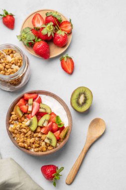 Tahta bir arka planda taze böğürtlen ve meyvelerle birlikte tahtadan bir kasede doğal yoğurt, kivi ve çilek. Sağlıklı ve besleyici kahvaltı konsepti. Üst görünüm ve kopyalama alanı.