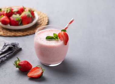 Bir bardak taze çilekli smoothie. Mavi arka planda naneli ve taze böğürtlen ve peçeteli. Yaz organik milkshake konsepti. Boşluğu kopyala.