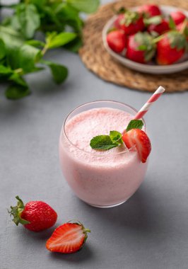 Mavi arka planda taze böğürtlen ve naneli bir bardak taze çilekli smoothie. Yaz organik milkshake konsepti. 