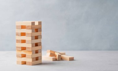 Hafif arka planda tahta oyun kulesi ve birkaç blok var. Ailenin entellektüel oyunu Jenga. Ön görünüm ve boşluk kopyala.