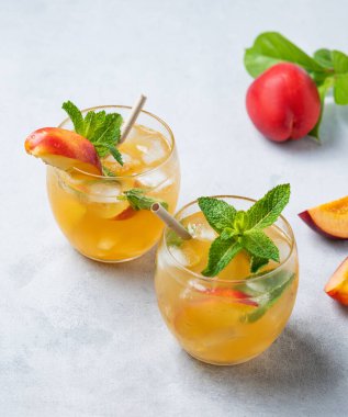 İki bardak şeftali kokteyli, limonata ya da arka planda buzlu çay. Buzlu, naneli ve taze meyveli soğuk alkolik ya da alkolsüz yaz içeceği kavramı. Üst görünüm.