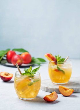 İki bardak şeftali kokteyli, limonata ya da arka planda buzlu çay. Buzlu, naneli ve taze meyveli soğuk alkolik ya da alkolsüz yaz içeceği kavramı. Boşluğu kopyala.