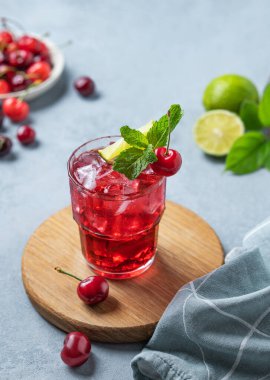 Nane, limon ve buzlu vişneli mojito kokteyli mavi arka planda ahşap bir tahtada taze böğürtlen ve peçeteyle. Yaz modasına uygun bir içecek konsepti.. 