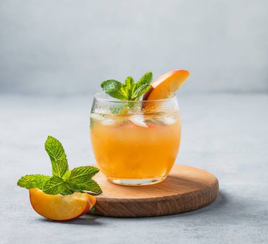Şeftali kokteyli, limonata ya da arka planda ahşap bir tahtada buzlu çay. Soğuk alkolik ya da alkolsüz, buzlu, naneli ve taze meyveli yaz içeceği kavramı. 