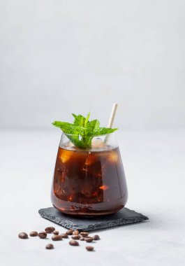 Naneli buzlu kahve espresso ve kahve çekirdekli siyah bir tahtada buz. Moda yazlık ferahlatıcı içecek. Boşluğu kopyala.