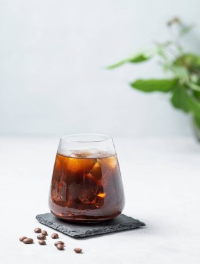 Kahveli espresso, siyah tahtada buzlu kahve çekirdeği ve yapraklı bir fonda. Moda yazlık ferahlatıcı içecek. Boşluğu kopyala.