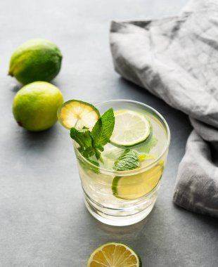 Naneli limonlu mojito ve bardakta buz. Peçeteyle arkaplandaki narenciye kokteylini tazeliyorum. Yaz soğuk limonata içecekleri konsepti. 