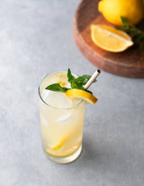 Limonlu, naneli ve buzlu mojito. Mavi arka planda ahşap tahtalı ve meyveli bir limonata. Yaz modasına uygun soğuk içecek konsepti. Üst görünüm.