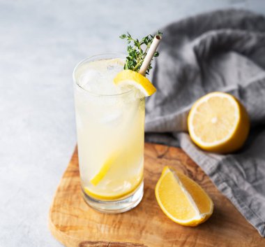 Limonlu, naneli ve buzlu mojito. Ahşap bir tahtada limonata, peçete ve mavi arka planda meyveler. Yaz modasına uygun soğuk içecek konsepti. Üst görünüm.