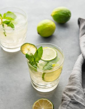 Naneli limonlu mojito ve bardakta buz. Peçeteyle arkaplandaki narenciye kokteylini tazeliyorum. Yaz soğuk limonata içecekleri konsepti. 
