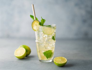 Uzun bardakta mojito kokteyli, limon, nane ve buzlu, mavi desenli arka planda yakın plan. Turunçgil meyveleriyle ferahlatıcı limonata içeceği konsepti. Boşluğu kopyala. 