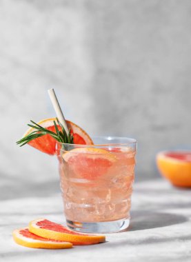 Biberiye ve buzlu greyfurt mojito kokteyli. Arka planda hafif bir bardakta. Taze narenciye dilimleri ve gölgesi var. Moda, yaz, sağlıklı ve ferahlatıcı limonata içeceği.. 