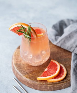 Biberiyeli greyfurt limonatası ve taze narenciye dilimli hafif arka planda tahta bir tahtanın üzerinde buz. Moda, yaz, sağlıklı ve ferahlatıcı kokteyl konsepti.