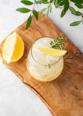 Taze limonlu, naneli ve buzlu mojito kokteyli. Hafif arka planda, ahşap bir tahtada yapraklı limonata içmek. Yaz modasına uygun soğuk içecek konsepti. Üst görünüm.