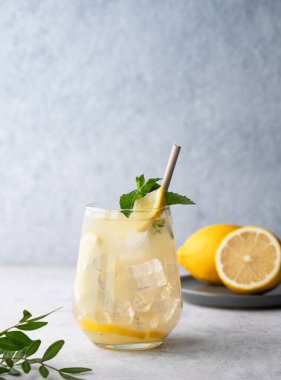 Taze limonlu, naneli ve buzlu mojito kokteyli. Hafif bir arka planda meyveli limonata içmek. Yaz modasına uygun soğuk içecek konsepti. Ön görünüm ve boşluk kopyala.