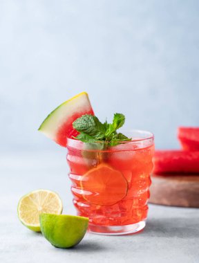 Karpuz, kireç, buz ve naneli mojito kokteyli. Arka planda hafif bir arkaplanda. Meyveler de yakında. Havalı yaz ferahlatıcı limonata içeceği konsepti. Ön görünüm.