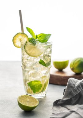 Limonlu, naneli ve buzlu uzun bardakta mojito kokteyli sabah ışığı ve gölgesi olan bir masada. Turunçgil meyveli limonata içeceği konsepti. 