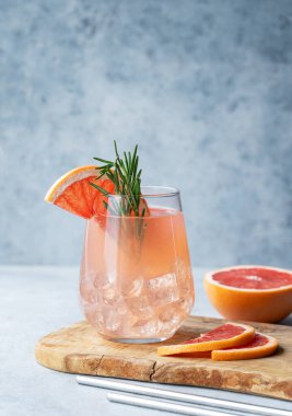 Biberiyeli greyfurt limonata içeceği ve mavi arka planda taze narenciye meyveli buzlu bir bardak. Moda, yaz, sağlıklı ve ferahlatıcı kokteyl konsepti. Ön görünüm ve boşluk kopyala