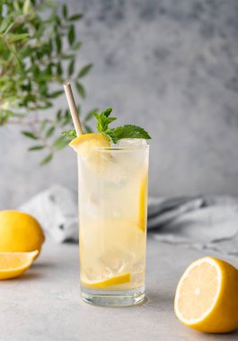 Limonlu, naneli ve buzlu mojito. Mavi arka planda, peçeteli ve meyveli bir limonata. Yaz modasına uygun soğuk içecek konsepti. Ön görünüm.