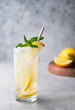 Limonlu, naneli ve buzlu mojito. Mavi arka planda ahşap tahtalı ve meyveli bir limonata. Yaz modasına uygun soğuk içecek konsepti. Ön görünüm.