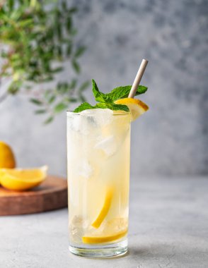 Limonlu, naneli ve buzlu mojito. Ahşap tahta, yaprak ve meyveli mavi bir zemin üzerinde turunçgil limonatası. Yaz modasına uygun soğuk içecek konsepti. Ön görünüm ve boşluk kopyala.