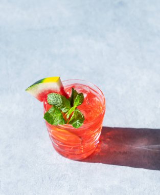 Mojito, karpuz, kireç, buz ve gölgeli açık arkaplanda bir bardakta nane şekeri ile içilir. Kokteyl menüsü için son moda limonata konsepti. Üst görünüm ve kopyalama alanı.