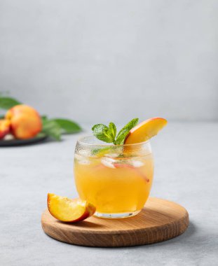 Şeftali kokteyli, limonata ya da arka planda ahşap bir tahtada buzlu çay. Buzlu, naneli ve taze meyveli soğuk alkolsüz yaz içeceği kavramı. Boşluğu kopyala.