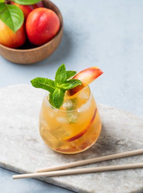 Şeftali kokteyli, limonata ya da mermer bir panoda hafif arka planda tüp ile buzlu çay. Buzlu, naneli ve taze meyveli soğuk alkolsüz yaz içeceği kavramı. Üst görünüm.