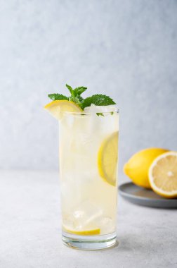 Limonlu, naneli ve buzlu mojito. Hafif bir arka planda meyveli limonata. Yaz modasına uygun soğuk içecek konsepti. Ön görünüm.