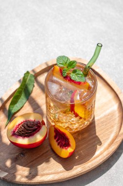 Buzlu şeftali ve naneli limonata. Beton zemin üzerinde tahta bir tahta üzerinde. Gölgeli bardakta taze buzlu çay. Bar ya da kafe menüsü için yaz içeceği tarifi konseptini tazeliyorum. Boşluğu kopyala. 