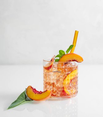 Şeftali ferahlatıcı içecek buzlu ve beyaz bir masada nane şekeri. Bardakta taze ev yapımı limonata. Bar veya kafe menüsü için yaz buzlu çay tarifi konsepti. Ön görünüm ve boşluk kopyala.