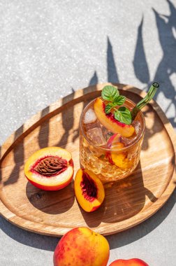 Buzlu şeftali ve naneli limonata. Beton zemin üzerinde tahta bir tahta üzerinde. Gölgeli bardakta taze buzlu çay. Bar ya da kafe menüsü için yaz içeceği tarifi konseptini tazeliyorum. Üst görünüm ve kopyalama alanı