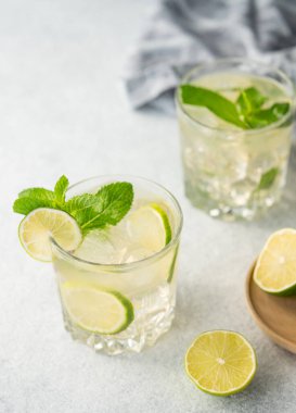 Hafif arka planda taze narenciye meyveli iki bardak limonlu kokteyl. Yaz ferahlatıcı mojito. Naneli ve buzlu içecek konsepti.. 