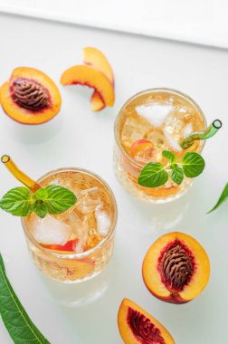 Buzlu şeftalili limonata ve beyaz arka planda nane şekeri. Bardakta taze buzlu çay ve pencereden gelen ışık. Bar ya da kafe menüsü için yaz içeceği tarifi konseptini tazeliyorum. Üst görünüm