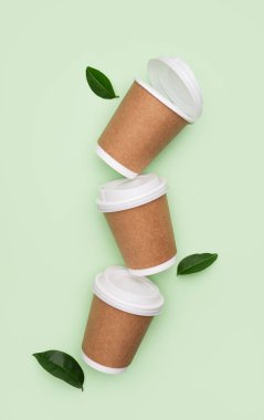 Yeşil kapaklı, yapraklı, kahverengi kahve fincanı. Çevre dostu ve dikkatli tüketim kavramı. Ürün ya da tasarım için minimalist bir model. Üst görünüm ve kopyalama alanı. 