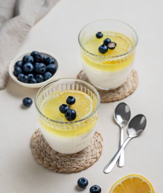 İki bardakta yaban mersinli kremalı panna cotta ve hafif arka planda taze çilek. Geleneksel İtalyan tatlı konsepti. Üst görünüm.