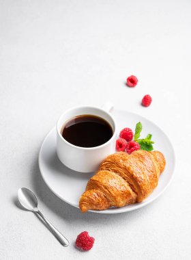 Bir fincan espresso kahve ve ay çöreği. Sabah ışığında beyaz desenli bir tabakta taze ahududu. Sağlıklı yemek ve Fransız kahvaltısı kavramı. Üst görünüm ve kopyalama alanı.