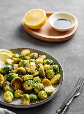 Soya ya ya da balzamik soslu gevrek Brüksel lahanası ve çatal ve limonlu koyu bir arka planda susam. Kırsal tarzda sağlıklı bir sebze yemeği kavramı.